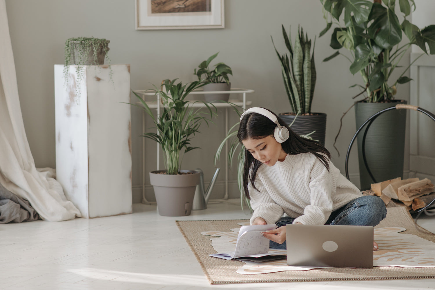 Woman wearing headphones working on her laptop in a room with plants
